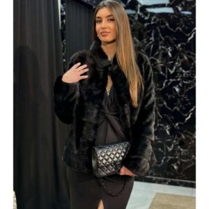 Crna duža bunda od prirodnog nerca sa kapom, dugmetom i pojasom, uz mogućnost skraćivanja, pruža luksuz i savršeno pristajanje.